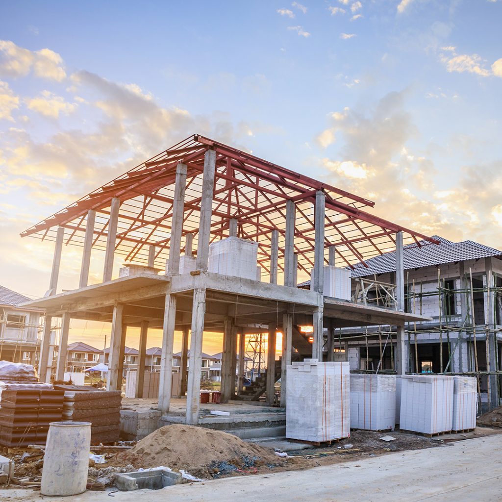 Construction site with a partially built house, featuring a steel frame, concrete pillars, and stacks of building materials, illustrating the long-term process of developing effective marketing strategies.