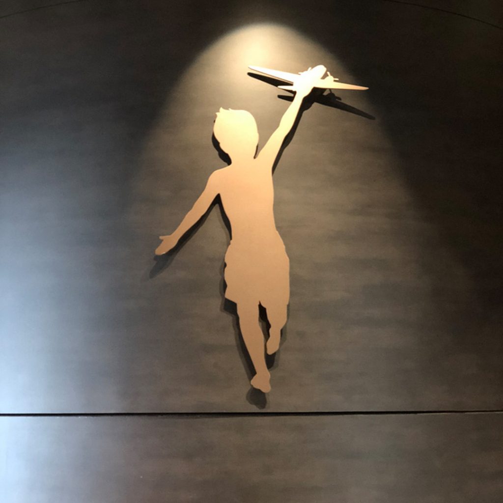 Silhouette of a child holding a toy airplane, symbolizing creativity and imagination, against a dark background, reflecting branding themes in marketing.